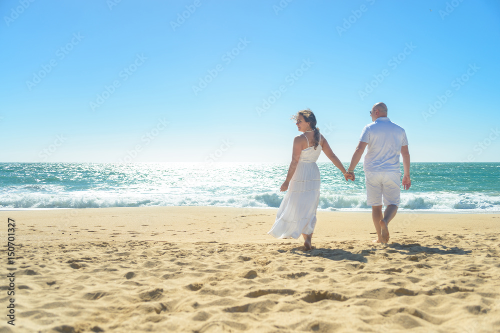 Young romantic couple walking on the beach holding hands Young romantic couple walking on the beach holding hands