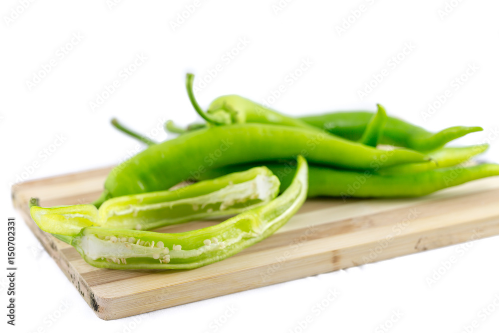 Small green peppers on cutting board with white background Small green peppers on cutting board with white background