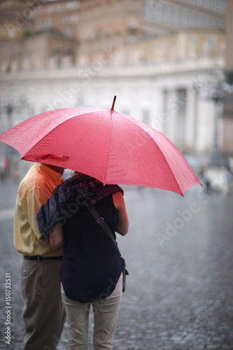 A man and a woman with an umbrella in the rain in St. Peter's Square in the Vatican. Rome, Italy