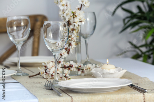 Beautiful festive table setting and branch of flowers in light room