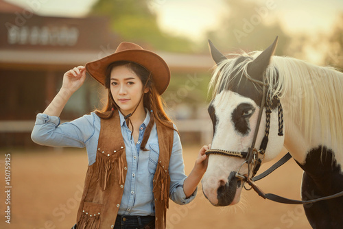 Beautiful woman sensuality elegance woman cowgirl on during sunset, Clothed blue jeans, brown leather jacket and hat. People and animals. Equestrian. vintage style © saravut