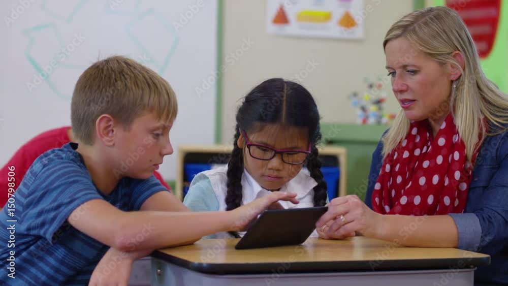 Teacher and students using digital tablet in school classroom Teacher and students using digital tablet in school classroom