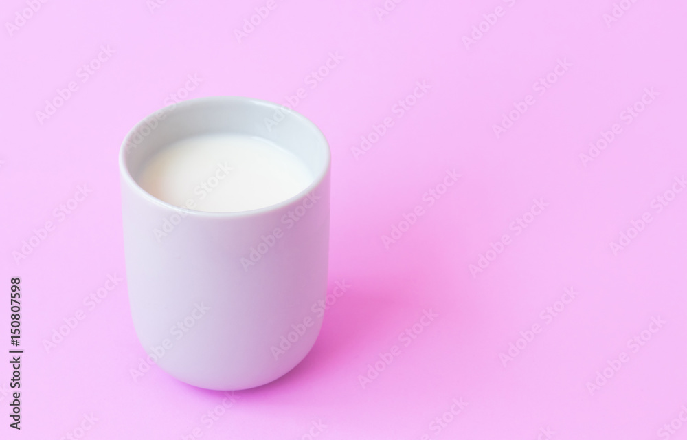 Milk in white ceramic cup on pink background, selective focus Milk in white ceramic cup on pink background, selective focus