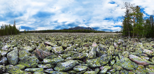 Spring panorama of Taganay stone river at cloudy sky background.