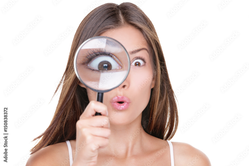 Funny expression. Shocked woman looking through a magnifying glass. Surprised Asian girl looking astonished discovering clues with big eyes through a magnifying glass, isolated on white background. Funny expression. Shocked woman looking through a magnifying glass. Surprised Asian girl looking astonished discovering clues with big eyes through a magnifying glass, isolated on white background.