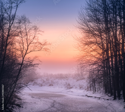 Foggy landscape with frozen river and sunset at evening in Finland
