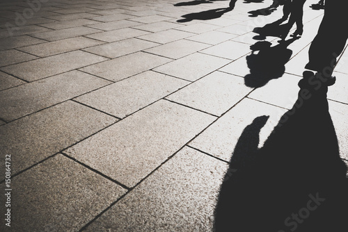 shadow of people in day light on pattern granite city street, copy space on left