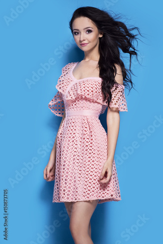 Beautiful smiling woman in pink dress on blue background