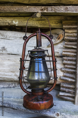 Old lantern for a candle on the background of a wooden wall. Oil lamp