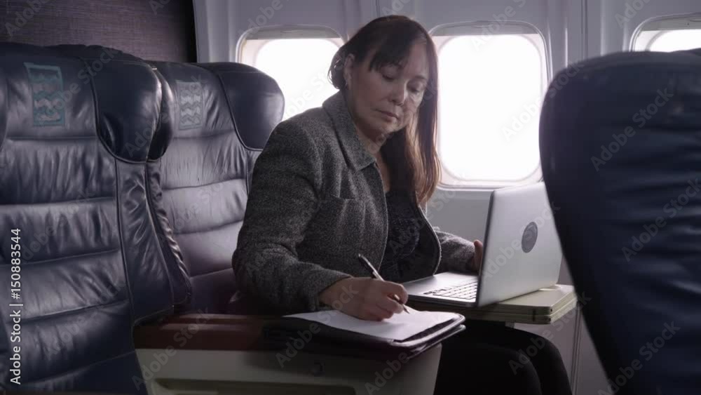 Businesswoman using laptop computer on airplane Businesswoman using laptop computer on airplane