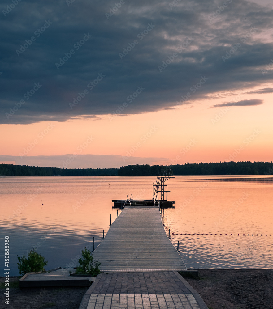 Landscape with pier and sunset at summer evening in the lake in Finland