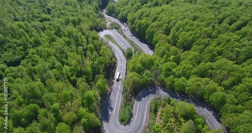 Winding road in the forest. Transylvania, Romania, Europe. Cars passing on road.
