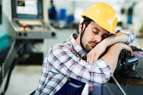 Obraz na plátně Tired worker fall asleep during working hours in factory