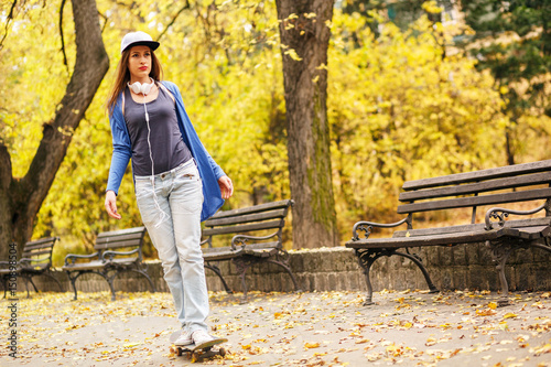 Young woman in park driving skateboard.