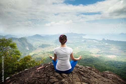 Young blonde woman practicing yoga and meditation in mountains during luxury yoga retreat in Bali, Asia