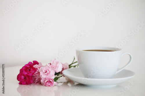 Cup of tea on white isolated background with flowers next to it