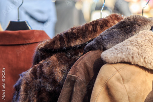 Vintage fur coats at a flea market in Europe. Used leather and suede clothing on garage sale or charity shop