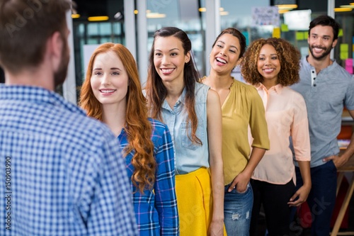 Smiling colleagues standing in front of male executive © WavebreakMediaMicro