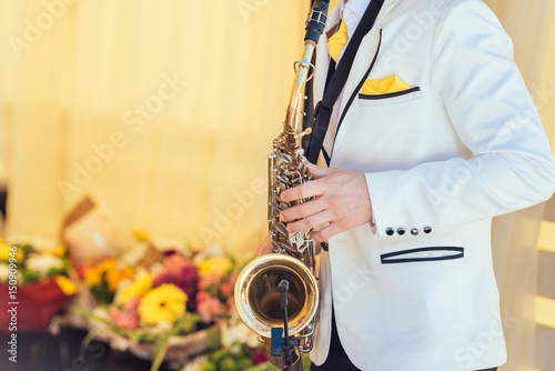 Canvas Print Saxophonist in white jacket plays the saxophone