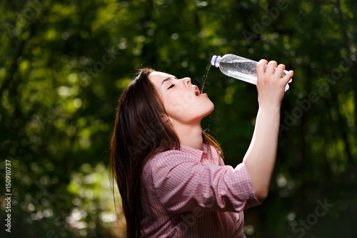 Happy beautiful young thirsty woman drinking water.