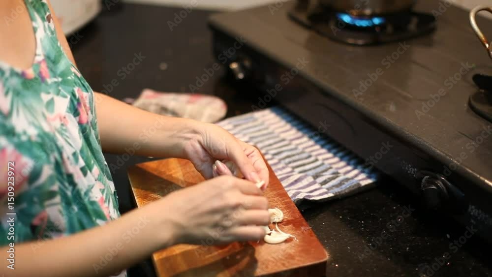 Shot of asian woman chef cutting, dice garlic clove on chopping wooden board. Shot of asian woman chef cutting, dice garlic clove on chopping wooden board.