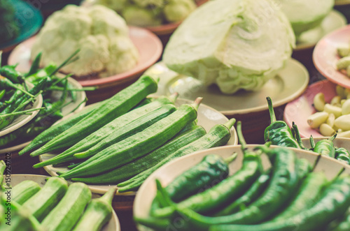 Various vegetables display on wooden table for sale at fresh market stall with faded color effect.