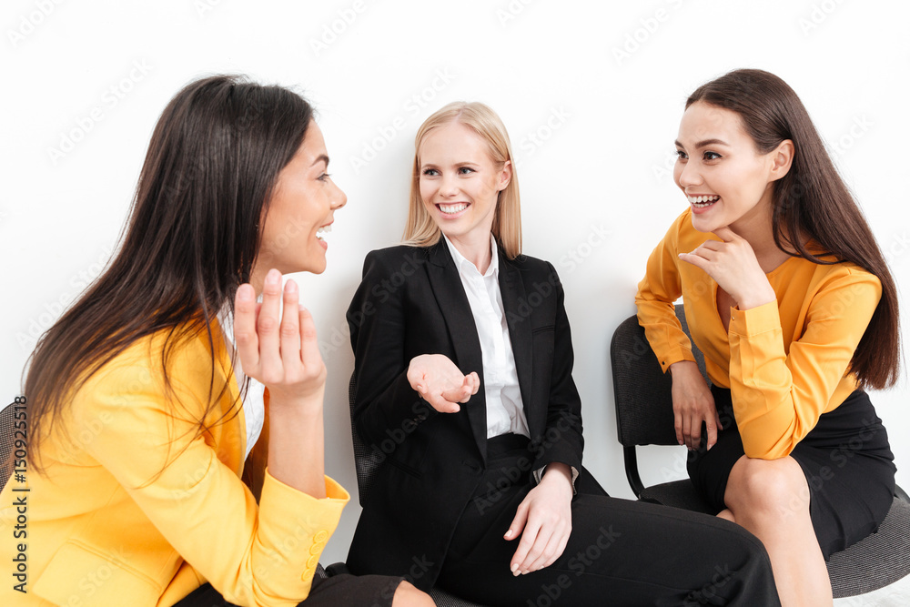 Happy colleagues women sitting in office talking with each other. Happy colleagues women sitting in office talking with each other.