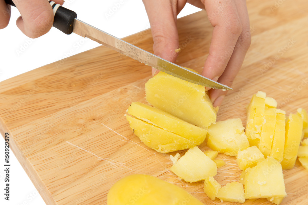 Chef cuts boiled potatoes on board on a white background Chef cuts boiled potatoes on board on a white background
