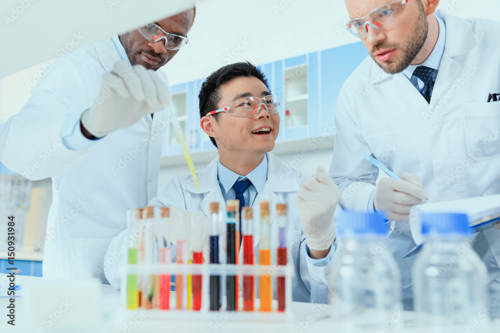 Professional scientists in white coats working together in chemical laboratory Professional scientists in white coats working together in chemical laboratory