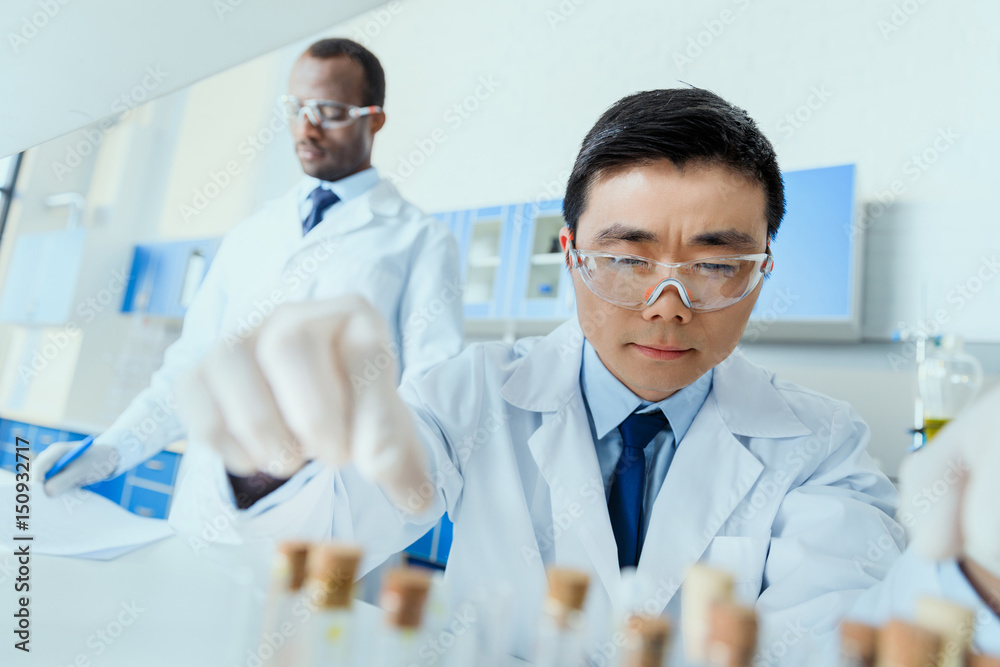 Professional scientists in white coats working together in chemical laboratory Professional scientists in white coats working together in chemical laboratory