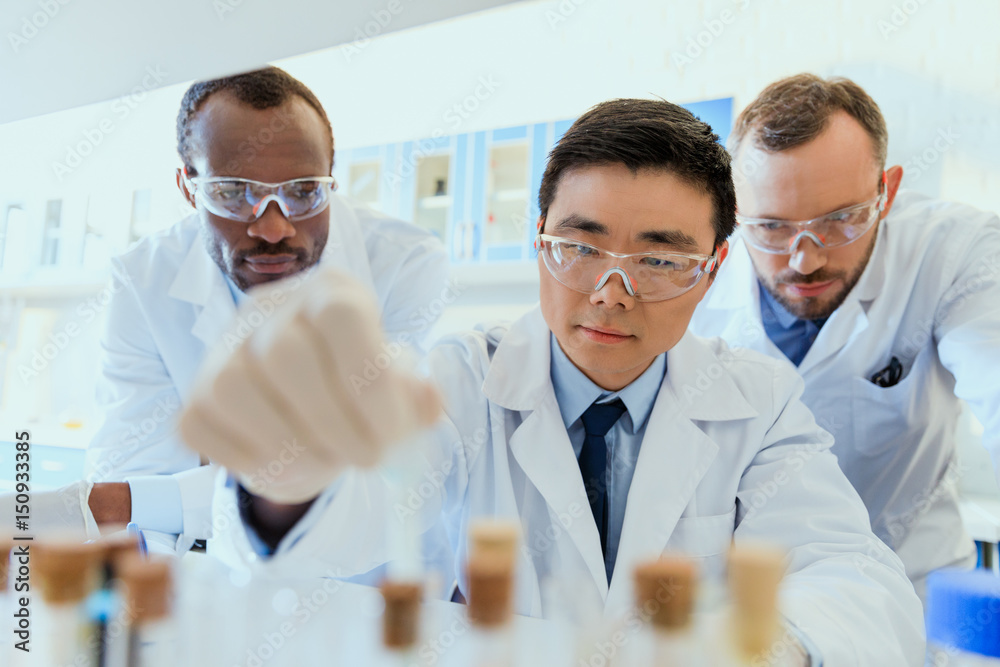 Multiethnic group of scientists in protective eyeglasses working together in chemical laboratory Multiethnic group of scientists in protective eyeglasses working together in chemical laboratory