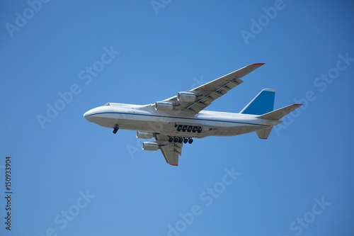 A white airplane flying in a clear pale blue sky.
