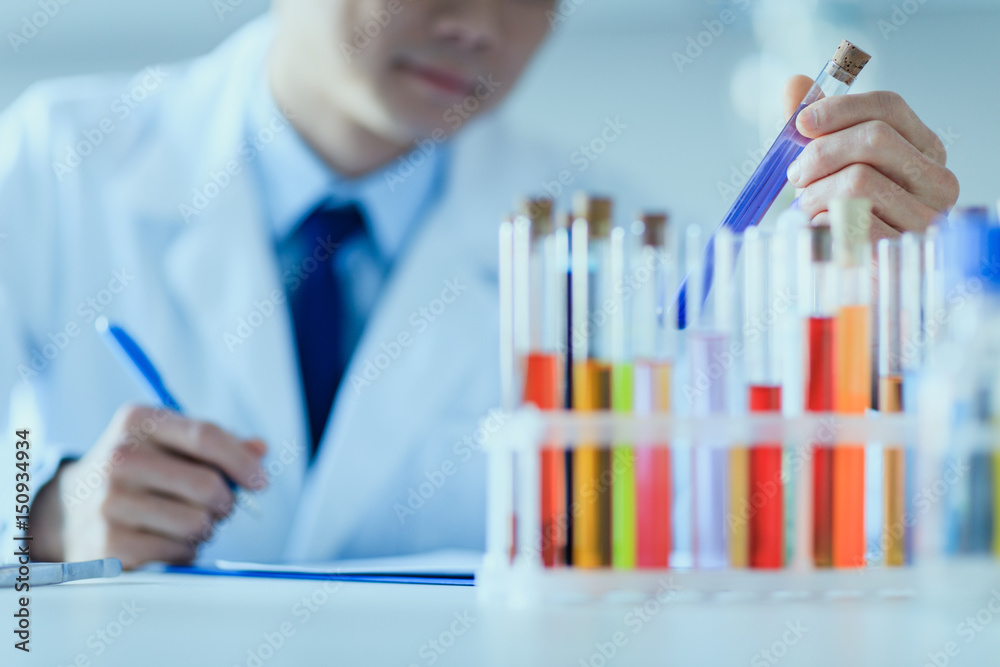 Cropped shot of scientist in lab coat holding test tube and taking notes, laboratory researcher concept Cropped shot of scientist in lab coat holding test tube and taking notes, laboratory researcher concept