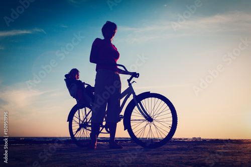 Fototapeta Naklejka Na Ścianę i Meble -  Silhouette of mother and baby biking at sunset