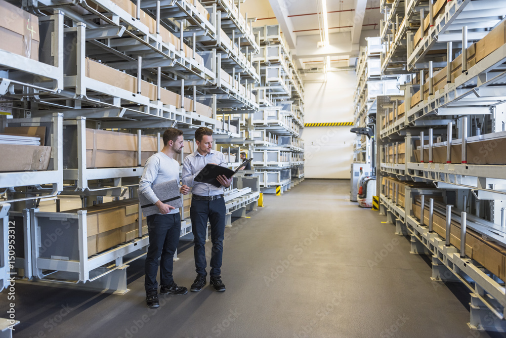 Two men talking in factory warehouse Two men talking in factory warehouse
