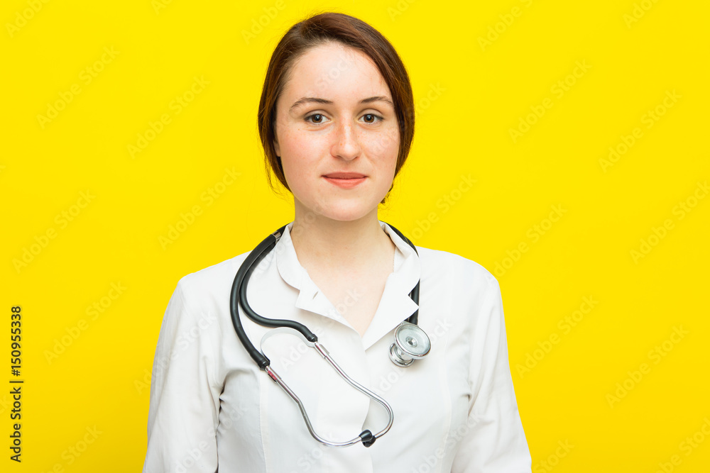 Young female doctor with a stethoscope on yellow background Young female doctor with a stethoscope on yellow background