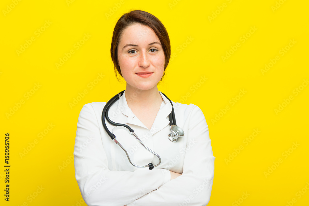 Young female doctor with a stethoscope on yellow background Young female doctor with a stethoscope on yellow background