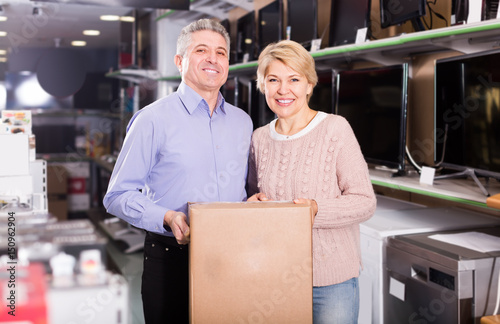 smiling mature married couple in shop packed household appliances into boxes © JackF