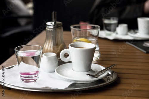 Espresso coffee, water, jug, sugar on wooden table.