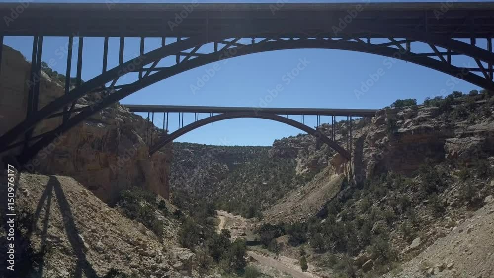 Aerial drone under Eagle Canyon Bridge Utah desert mountain. Double span interstate I-70 highway crosses deep gorge. Travel traffic overhead drone view. San Rafael Reef. Wilderness desert environment.