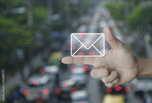 Mail icon on finger over blur of rush hour with cars and road, Contact us concept