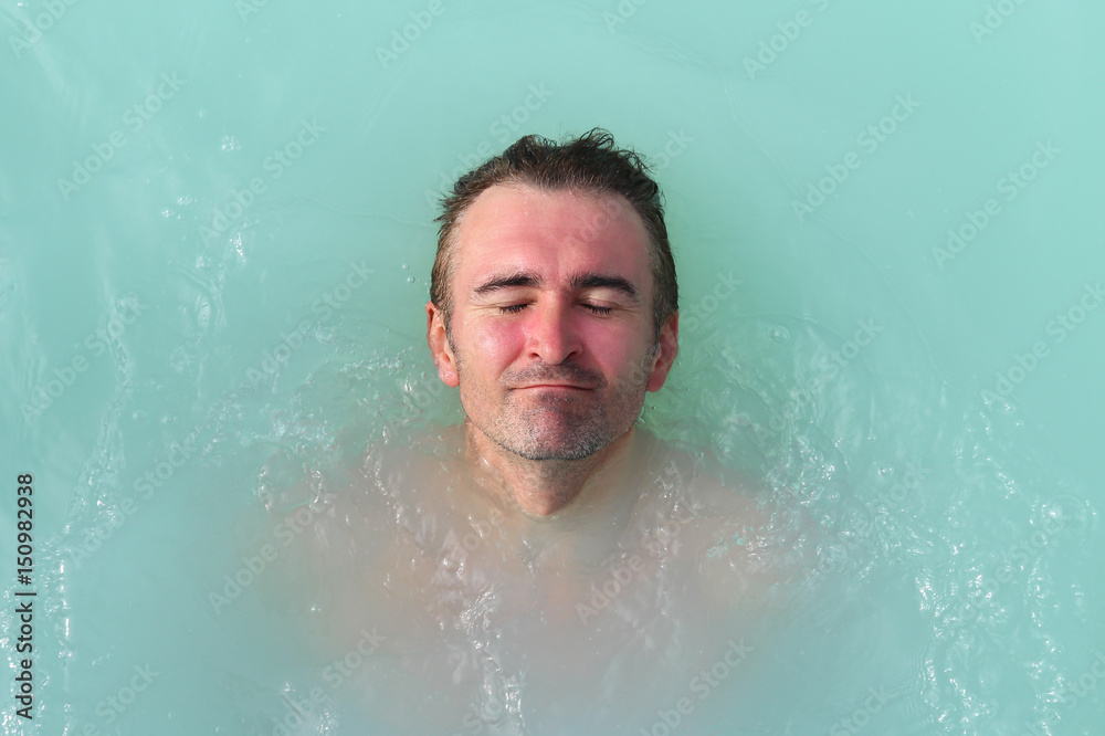 Man enjoys spa in hot spring Blue Lagoon in Iceland Man enjoys spa in hot spring Blue Lagoon in Iceland