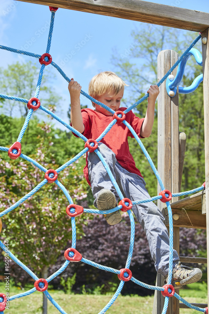 Child boy climbing rope web on the children playground outdoors at summer Child boy climbing rope web on the children playground outdoors at summer