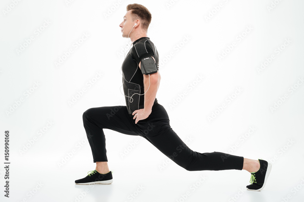 Obraz premium Side view of a young healthy sportsman stretching legs