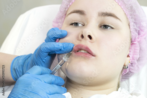 The process of cosmetic surgery of water injection in the area of the lips of a woman   