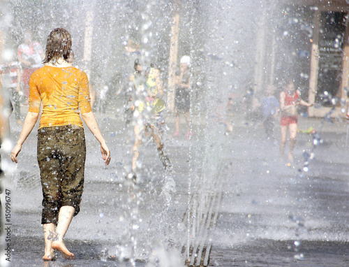 Woman in the fountain between the water jets