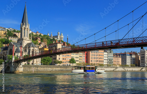 Tour boat passing a footbridge over the Saone at the Church of Saint Georges in Lyon, France.