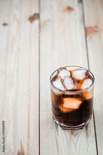 soft drinks. Cola glass with ice cubes on a wood background