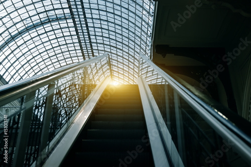 Escalator moving up at indoors in building with transparent roof