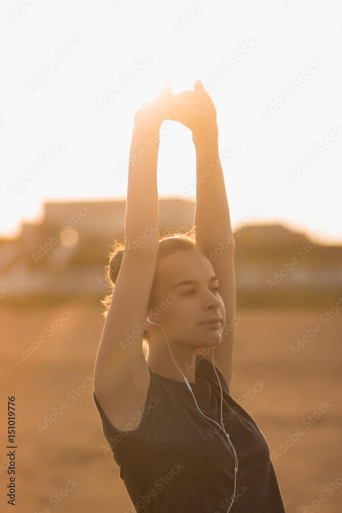 Young girl practices yoga on the beach in the morning at the dawn of the sun
